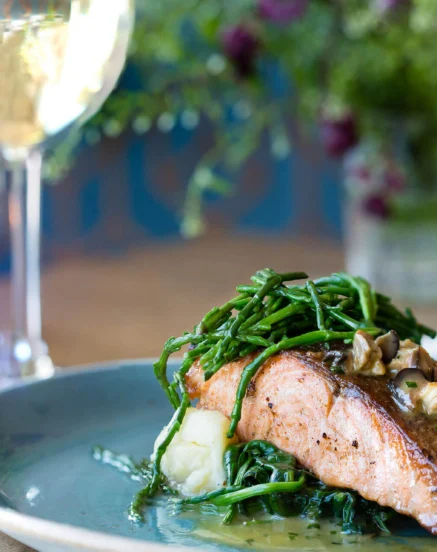 Elegant salmon dish with greens, accompanied by a glass of white wine at The Galmont Hotel & Spa.