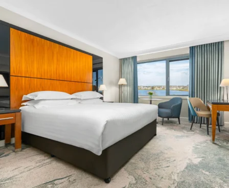 Bright hotel room with sea view, double bed, and elegant furnishings.