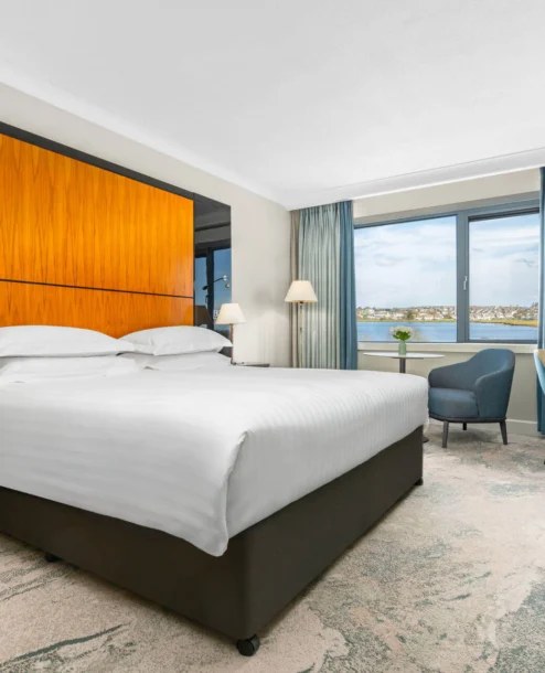 Bright hotel room with sea view, double bed, and elegant furnishings.