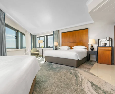 Bright hotel room with sea view, double bed, and seating area. Modern and inviting space.