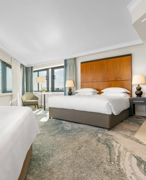 Bright hotel room with sea view, double bed, and seating area. Modern and inviting space.