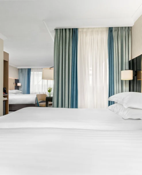 Elegant hotel room with plush white bedding and a serene view.
