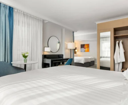 Modern hotel room with double beds, cosy seating area, and warm ambient lighting.