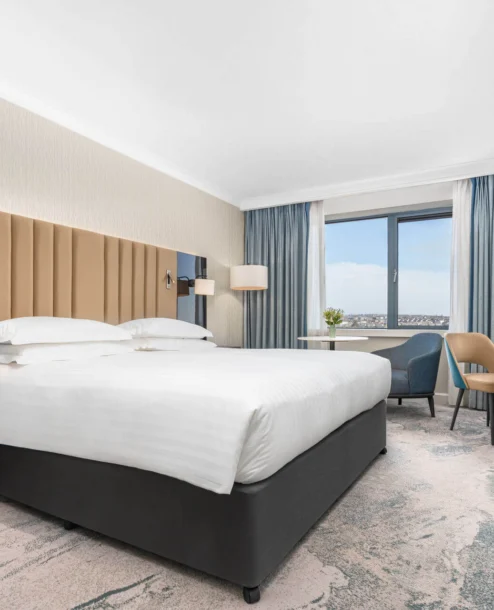 Elegant hotel room at The Galmont with a king-sized bed, work desk, and scenic window view.