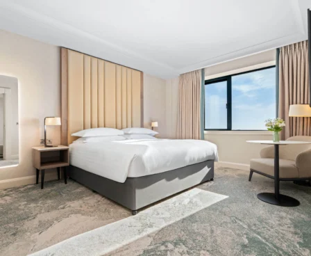 Elegant hotel room with large bed, cosy seating, and window view at The Galmont Hotel.