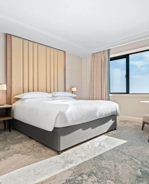 Elegant hotel room with large bed, cosy seating, and window view at The Galmont Hotel.