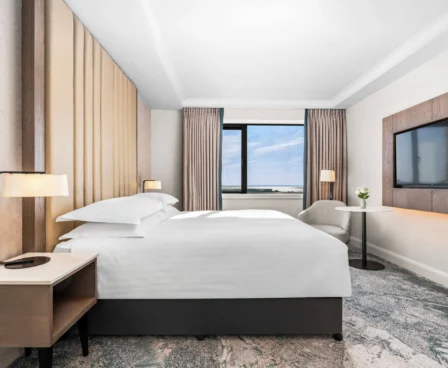 Modern hotel room with a cosy double bed, large window, and a scenic view.