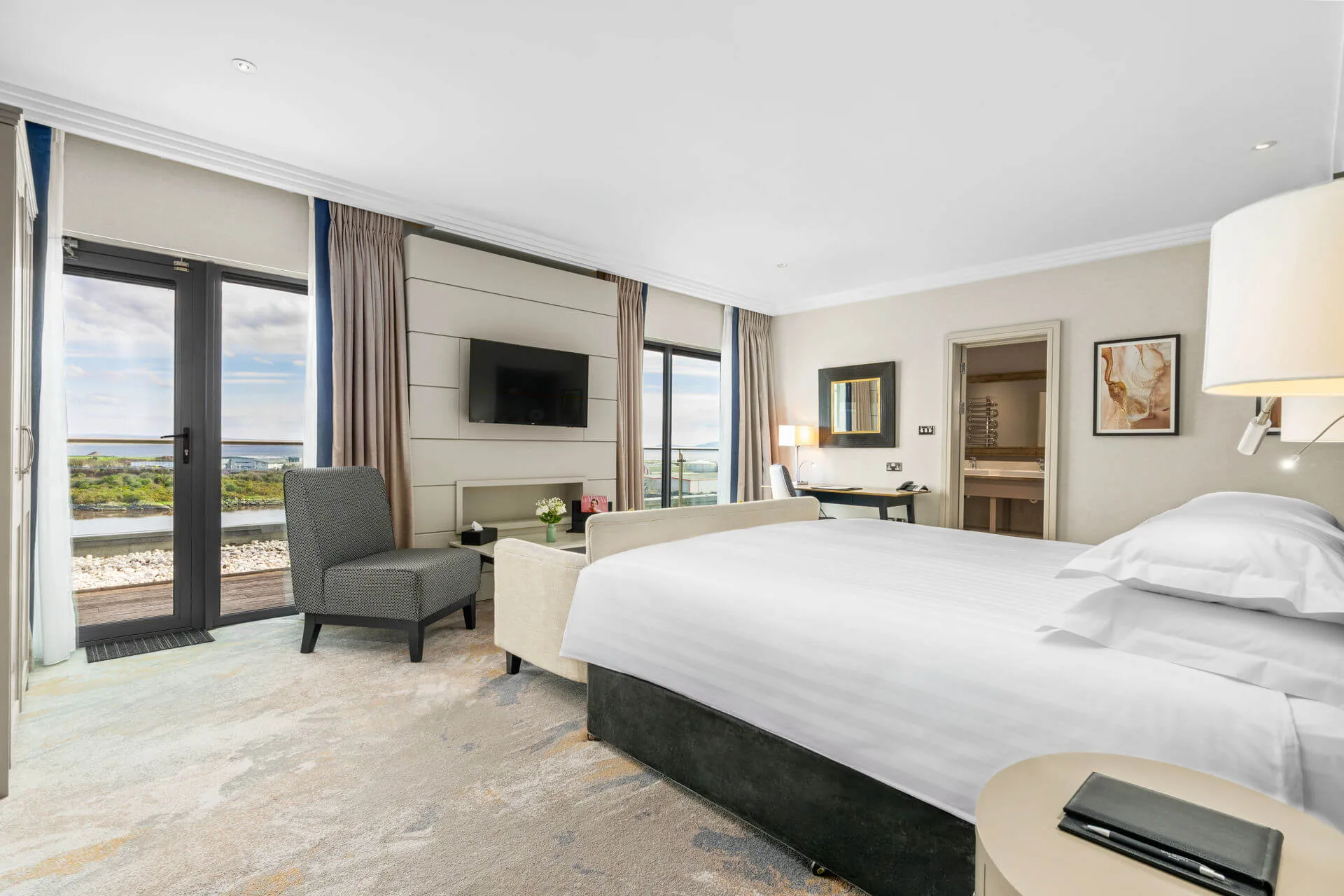 Elegant hotel room with a sea view and cosy seating area.