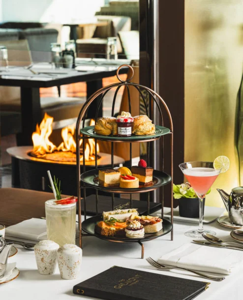 Elegant afternoon tea setup with desserts and drinks by a cosy fireplace at The Galmont.
