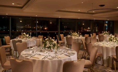 Elegant dining area set for a romantic evening, with softly lit tables and floral centrepieces.