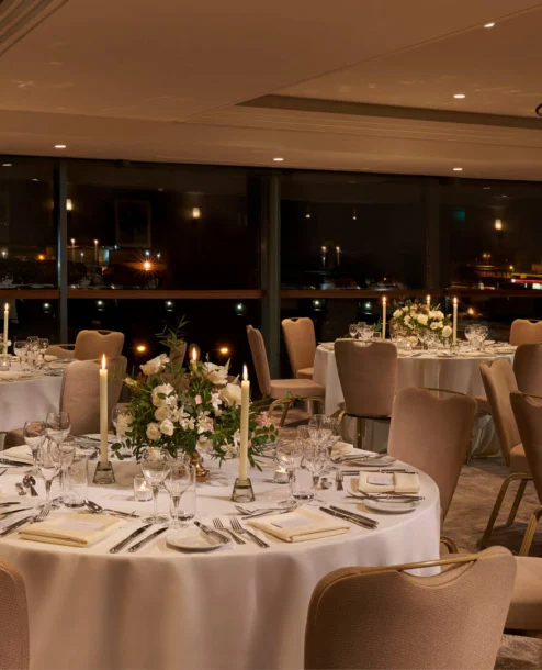 Elegant dining area set for a romantic evening, with softly lit tables and floral centrepieces.