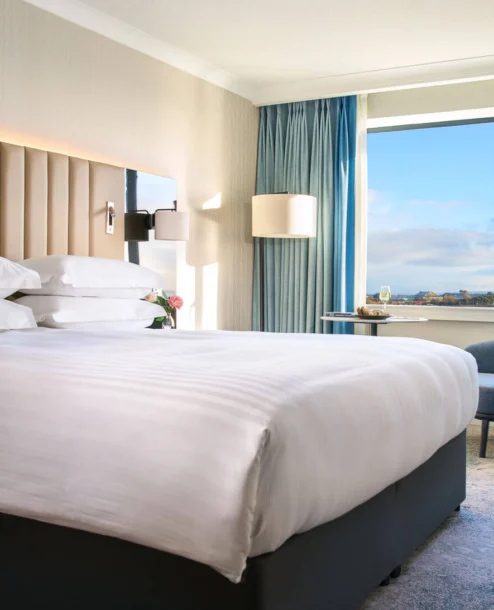 Elegant hotel room with a king-size bed, ocean view and cosy seating area at The Galmont Hotel.