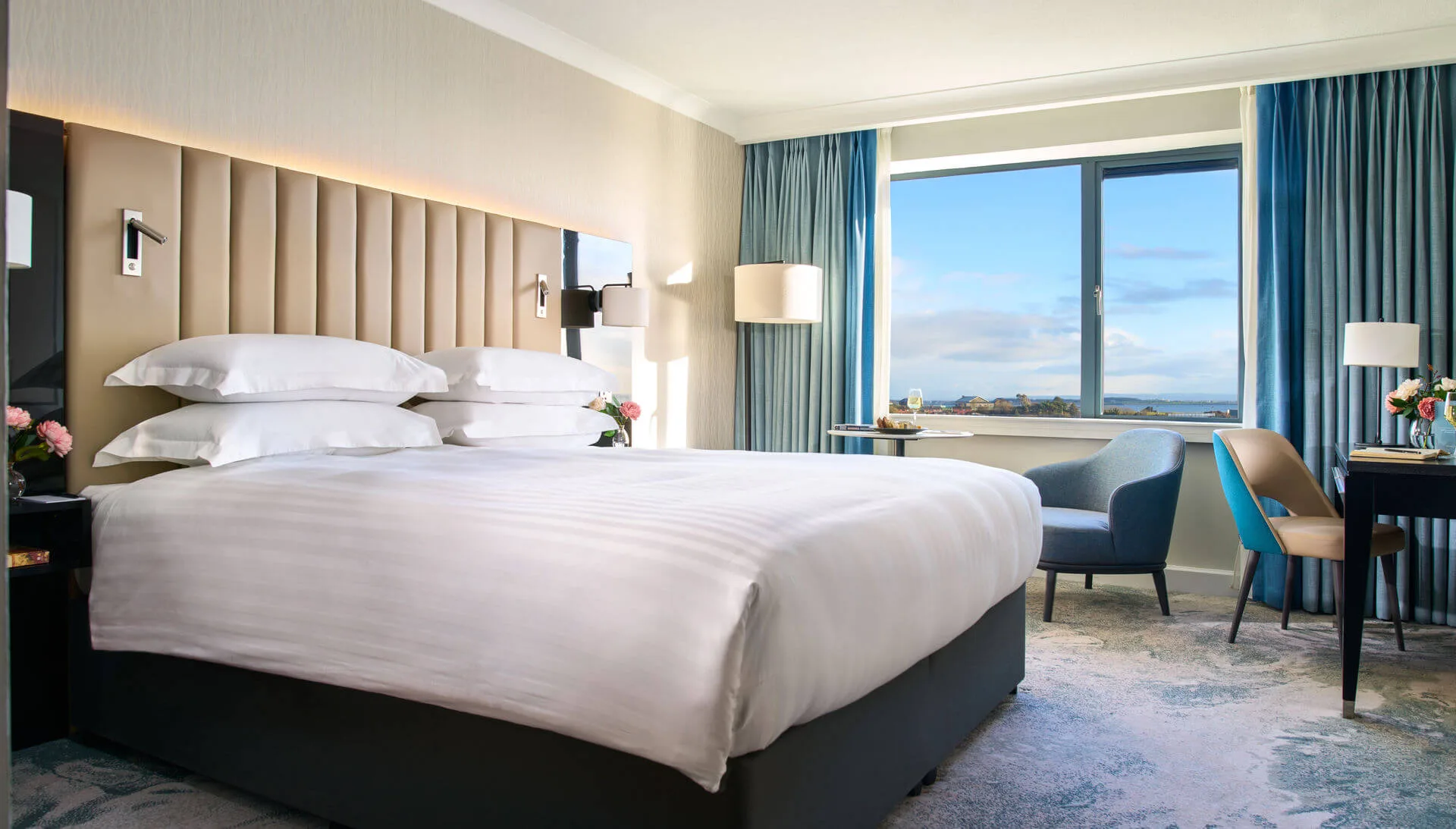 Elegant hotel room with a king-size bed, ocean view and cosy seating area at The Galmont Hotel.