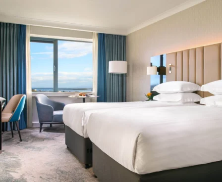 Elegant hotel room with sea view, twin beds, and a cosy seating area.