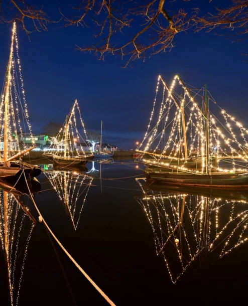 Illuminated boats reflecting on serene water at The Galmont Hotel & Spa harbour.