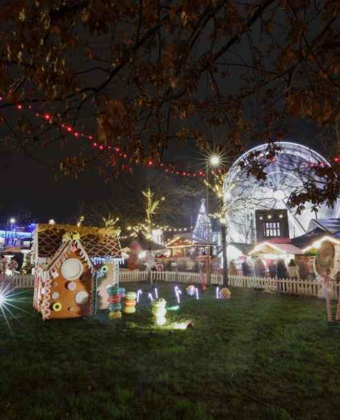 Festive family enjoying illuminated fairground at night.
