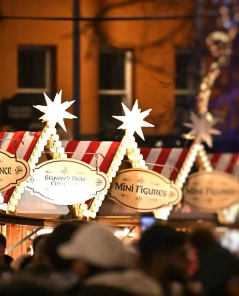 Festive market scene with joyful families enjoying food stalls at night.