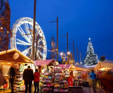 Festive Christmas market with families shopping near a lit Ferris wheel and Christmas tree.