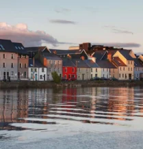 Colourful waterfront townhouses reflecting in calm evening waters.