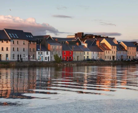Colourful waterfront townhouses reflecting in calm evening waters.