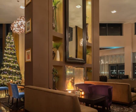 Cosy hotel lounge with a glowing fireplace and Christmas tree, inviting evening ambience.