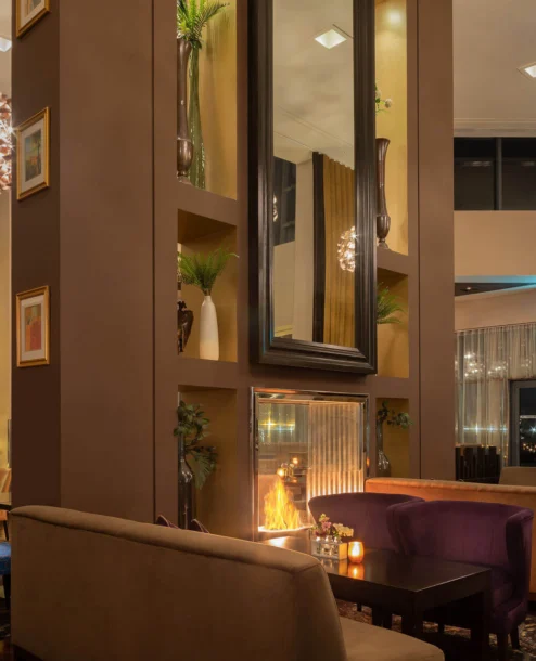 Cosy hotel lounge with a glowing fireplace and Christmas tree, inviting evening ambience.