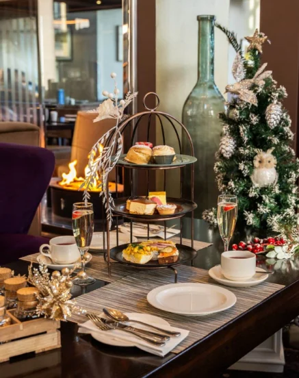 Cosy afternoon tea setup by the fireplace with festive decorations.