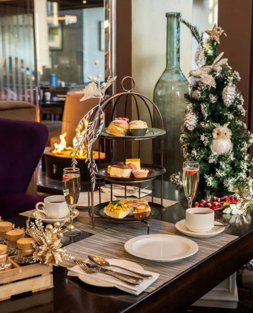 Cosy afternoon tea setup by the fireplace with festive decorations.