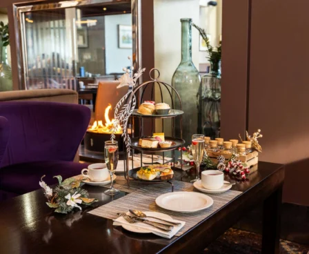 Cosy hotel lounge setting with afternoon tea display near a fireplace.