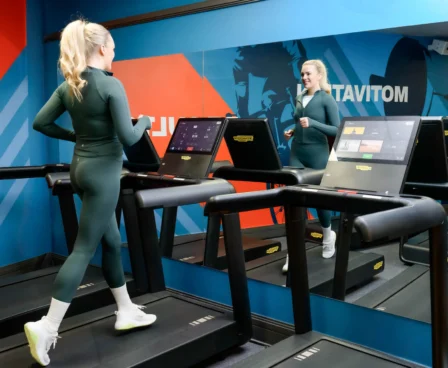 Woman jogging on treadmill in hotel gym with vibrant wall art.