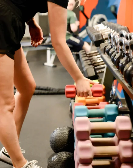 A guest selects a dumbbell in a modern hotel gym.