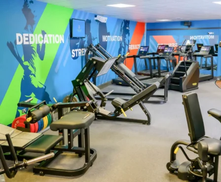 Family enjoying workout in vibrant hotel gym, with colourful walls and modern equipment.