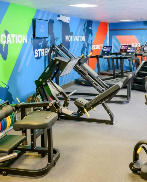 Family enjoying workout in vibrant hotel gym, with colourful walls and modern equipment.