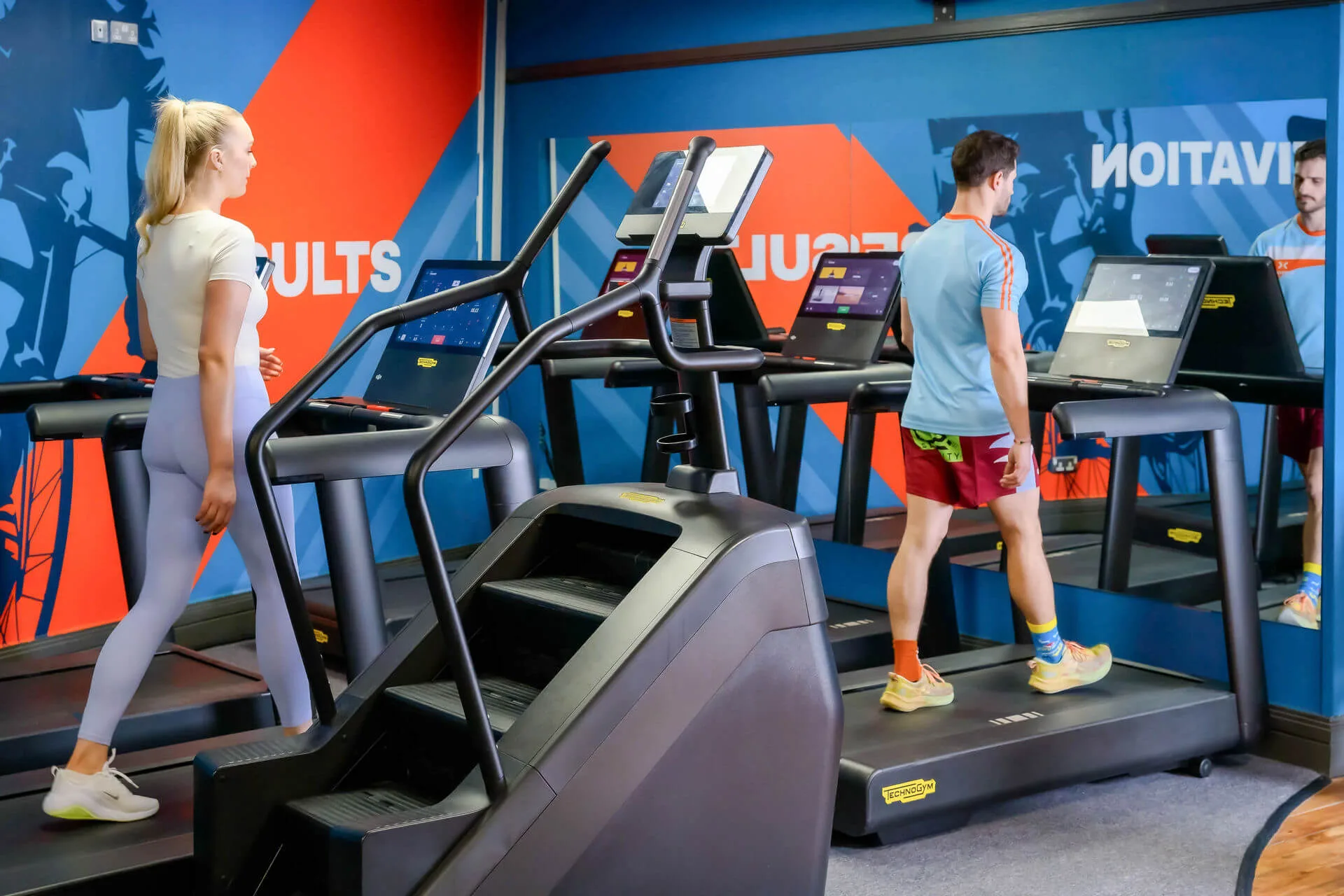 Family enjoys treadmill workout in colourful hotel gym.