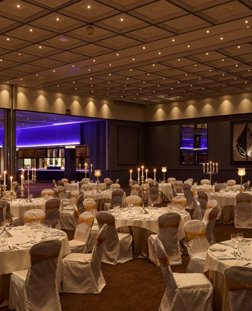 Elegant hotel ballroom set for an evening event with candlelit tables.