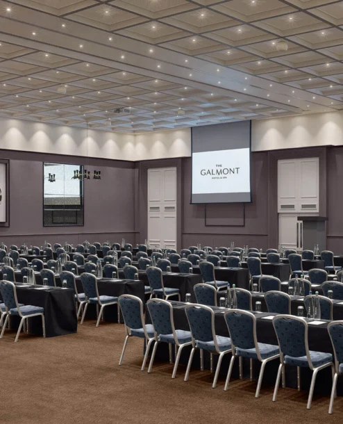 Spacious conference room at The Galmont Hotel & Spa with rows of seating and presentation screens.
