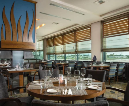 Elegant hotel restaurant with set tables by large windows offering a scenic view.