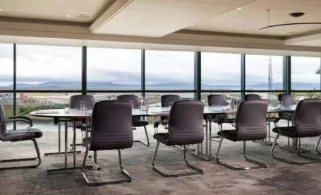 Conference room with panoramic view at The Galmont Hotel & Spa. TABLEs, chairs, and large windows.