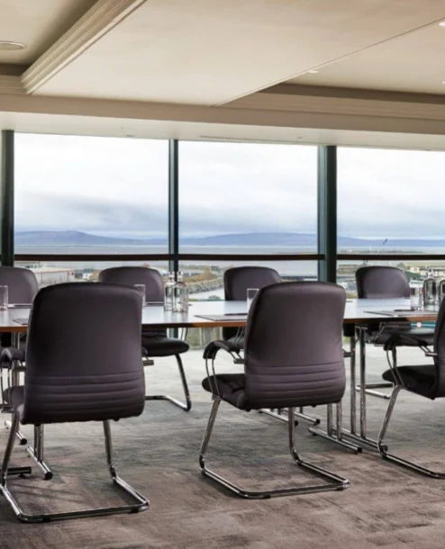 Conference room with panoramic view at The Galmont Hotel & Spa. TABLEs, chairs, and large windows.