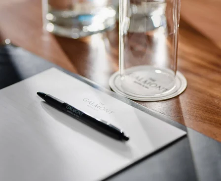 Elegant meeting setup with Galmont-branded pen and notepad on a polished wooden table.