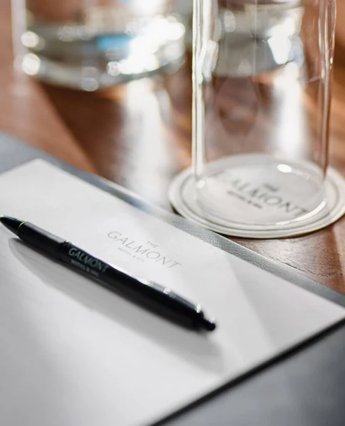 Elegant meeting setup with Galmont-branded pen and notepad on a polished wooden table.