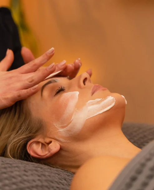 Woman enjoys a relaxing facial treatment at a spa, creating a serene atmosphere.