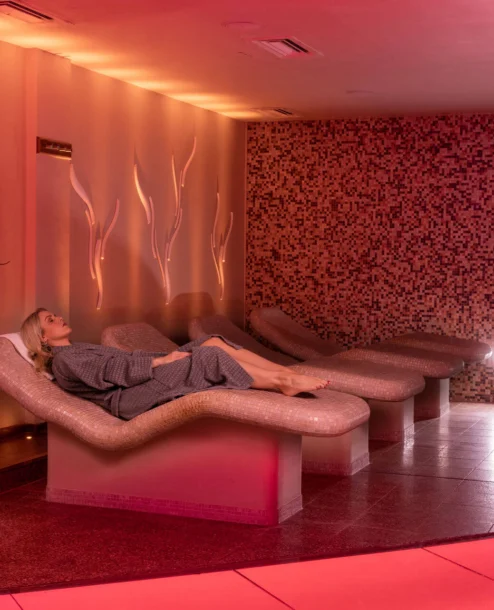 Woman relaxing in Galmont Hotel spa lounge with warm lighting and soothing ambience.