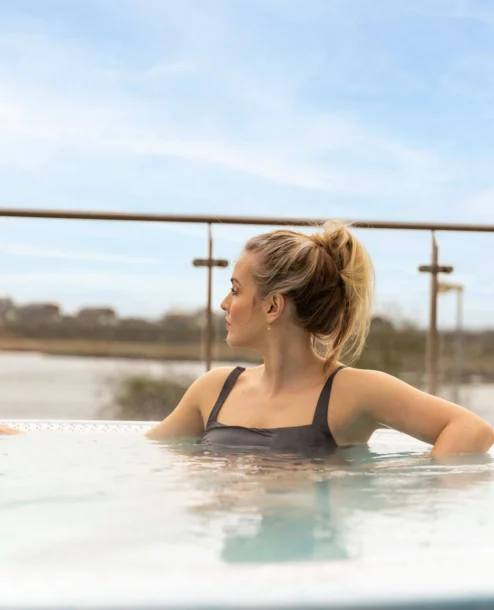 A woman relaxes in a hot tub overlooking a scenic lake view at The Galmont Hotel & Spa.