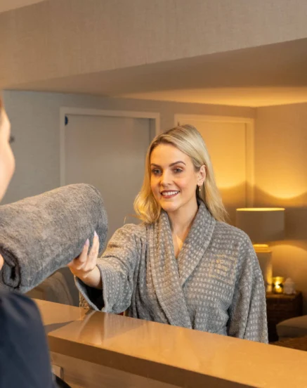 Friendly staff member offers towel to guest at The Galmont Hotel & Spa reception.