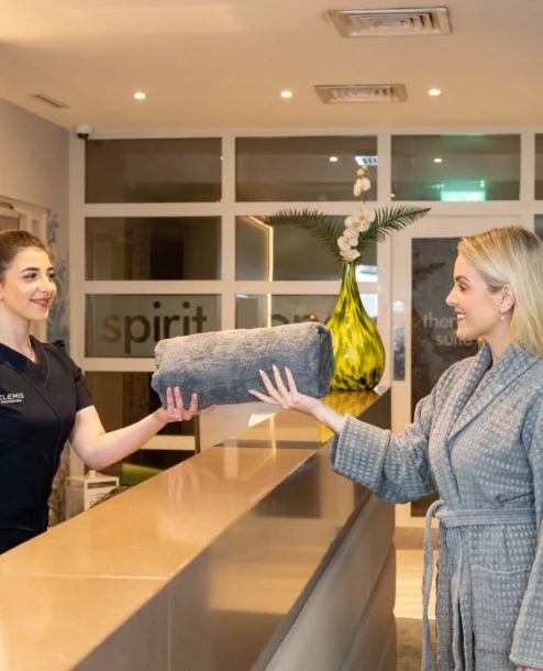 Hotel guest receiving fresh towel at spa reception.