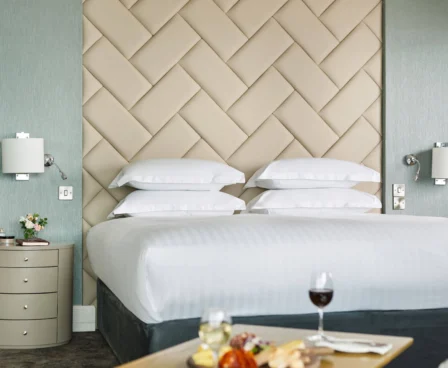 Elegant hotel room with plush bed and a tray of wine and snacks.