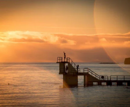 Family enjoys sunset at diving platform by calm sea near The Galmont Hotel.