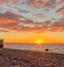 Beautiful sunset over Galway Bay near The Galmont Hotel & Spa, with colourful sky and pebbled shore.