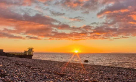 Beautiful sunset over Galway Bay near The Galmont Hotel & Spa, with colourful sky and pebbled shore.